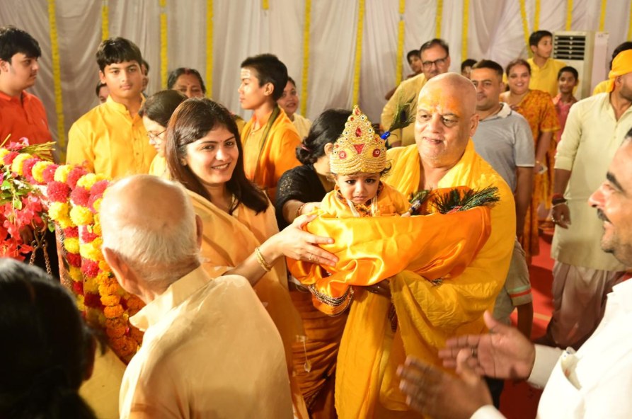 Child dressed as Krishna carried through the celebration
